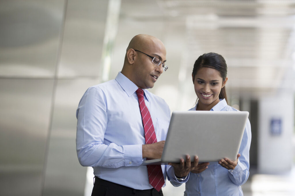 business colleagues standing in an office and looking at data on a computer